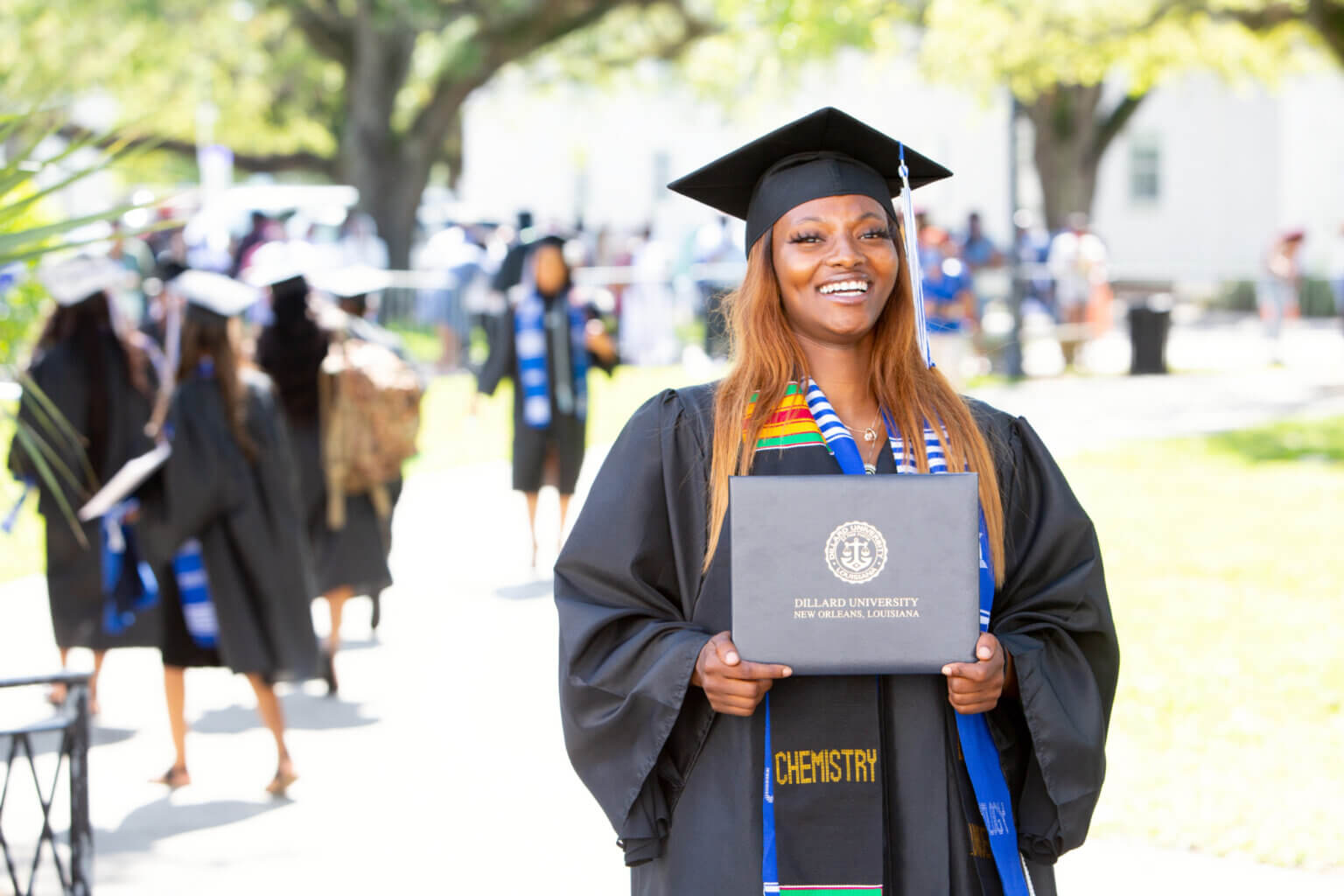 Dillard University student at graduation holding diploma