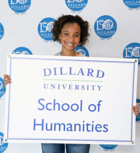 student holding school of humanities sign